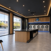 Interior de lavandería autoservicio Riowash con maquinaria profesional, madera y detalles de luz azul
